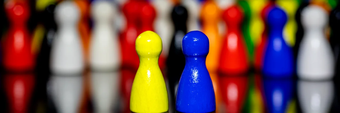 Colourful wooden game pawns lined up on a glossy black table