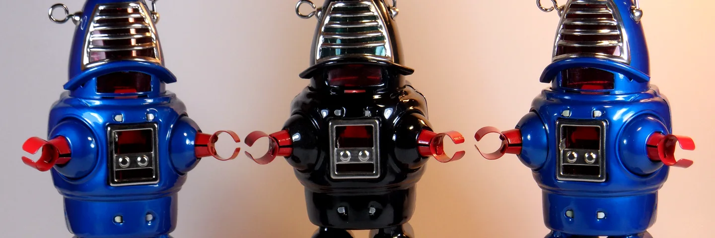 Three vintage-style tin wind-up robots standing in a row